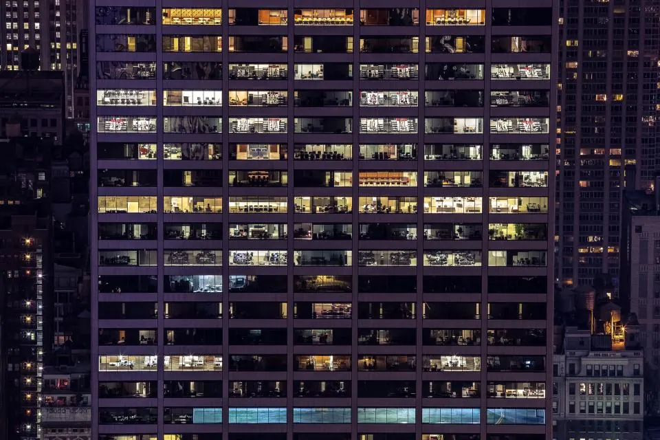 Rows of lit office windows in a tall building at night