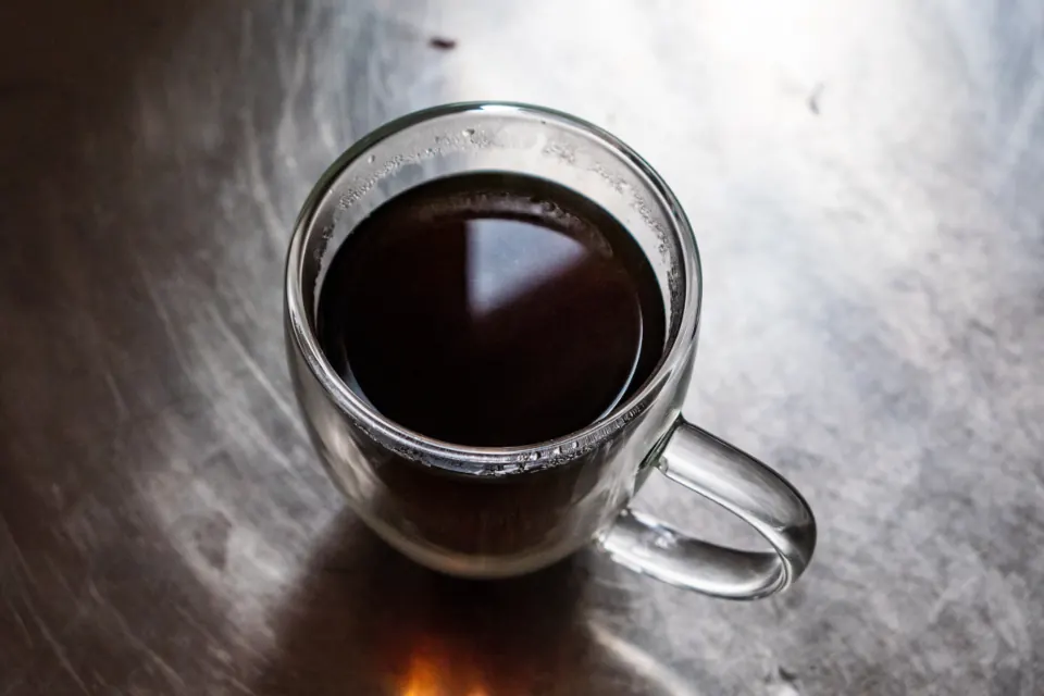 Glass mug of black coffee on a dark table