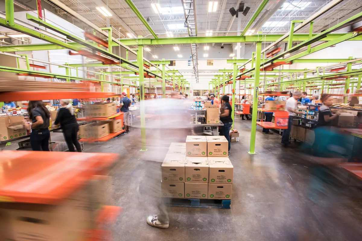 Warehouse floor with boxes stacked on a pallet as workers move past in a blur