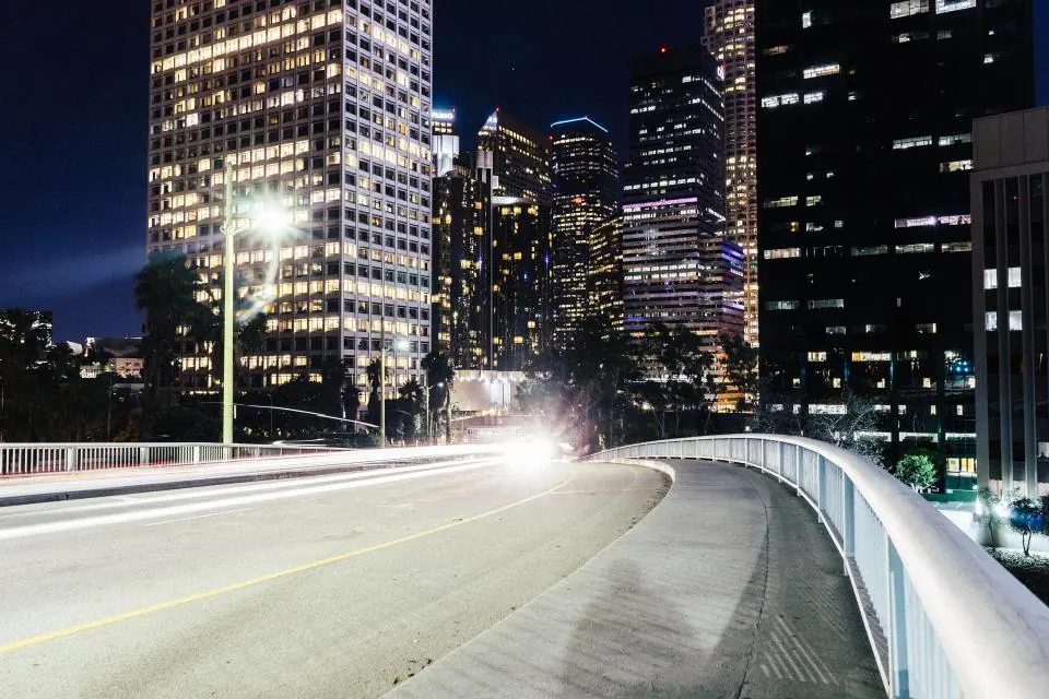 Empty road curving into a city lit up at night